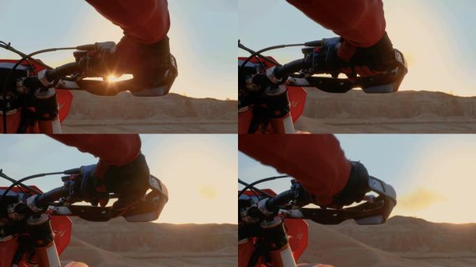 摩托车手扭转油门手柄的特写，而站在风景优美的采石场越野地形在日落。