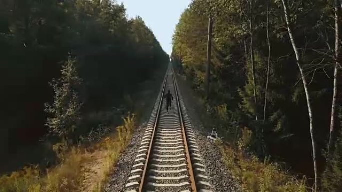 在铁路线之间奔跑的人。无人机后视图。运动员冲向秋季森林铁路的新视角