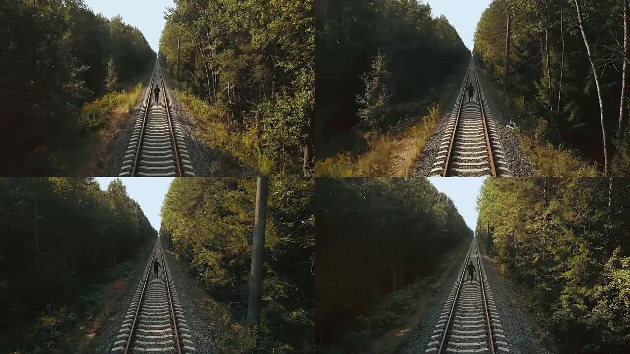 在铁路线之间奔跑的人。无人机后视图。运动员冲向秋季森林铁路的新视角