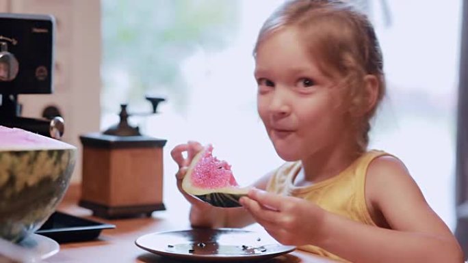 可爱的小女孩在厨房里吃一片西瓜的肖像。女性转身，看着镜头大笑