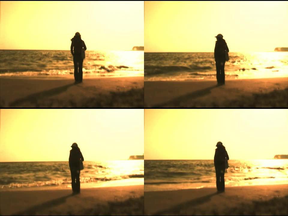 自由独立的女人在黄色的日落中站在海边