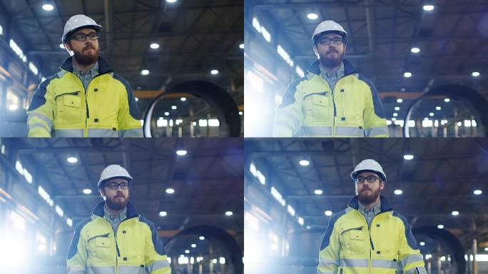 戴着安全帽的工业工程师戴着安全帽挥手致意，走过各种金属加工工艺的重工业制造厂。