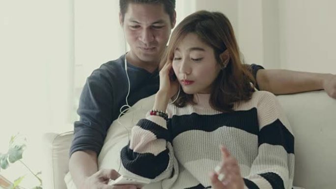 年轻的亚洲夫妇在家听音乐。