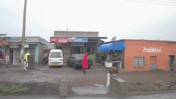 特写: 在泥泞的道路上行驶，经过贫穷的非洲小镇的五颜六色的街头商店