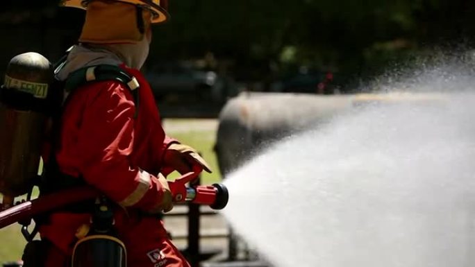 消防员使用灭火器和水管中的水进行消防。在危险情况下，消防员穿着消防服以确保安全。