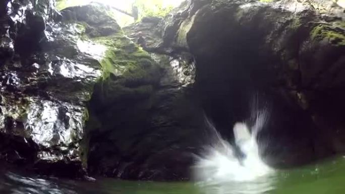 POV: 男人在河里游泳观察朋友跳下陡峭的岩石悬崖