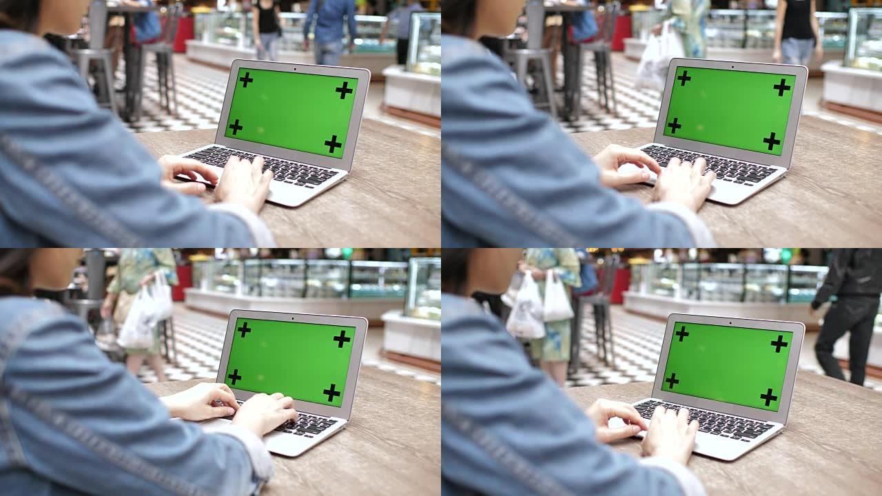 女人在绿屏购物中心寻找和使用笔记本电脑