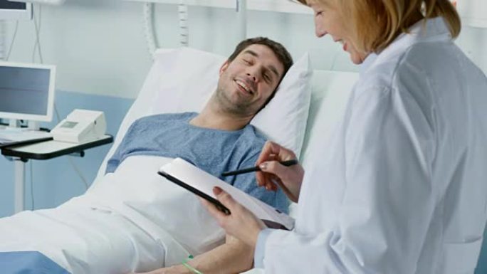 专业的女医生拜访躺在床上的康复中的男性患者，她提出问题并使用平板电脑填写病历。友好的保健医生对病人微