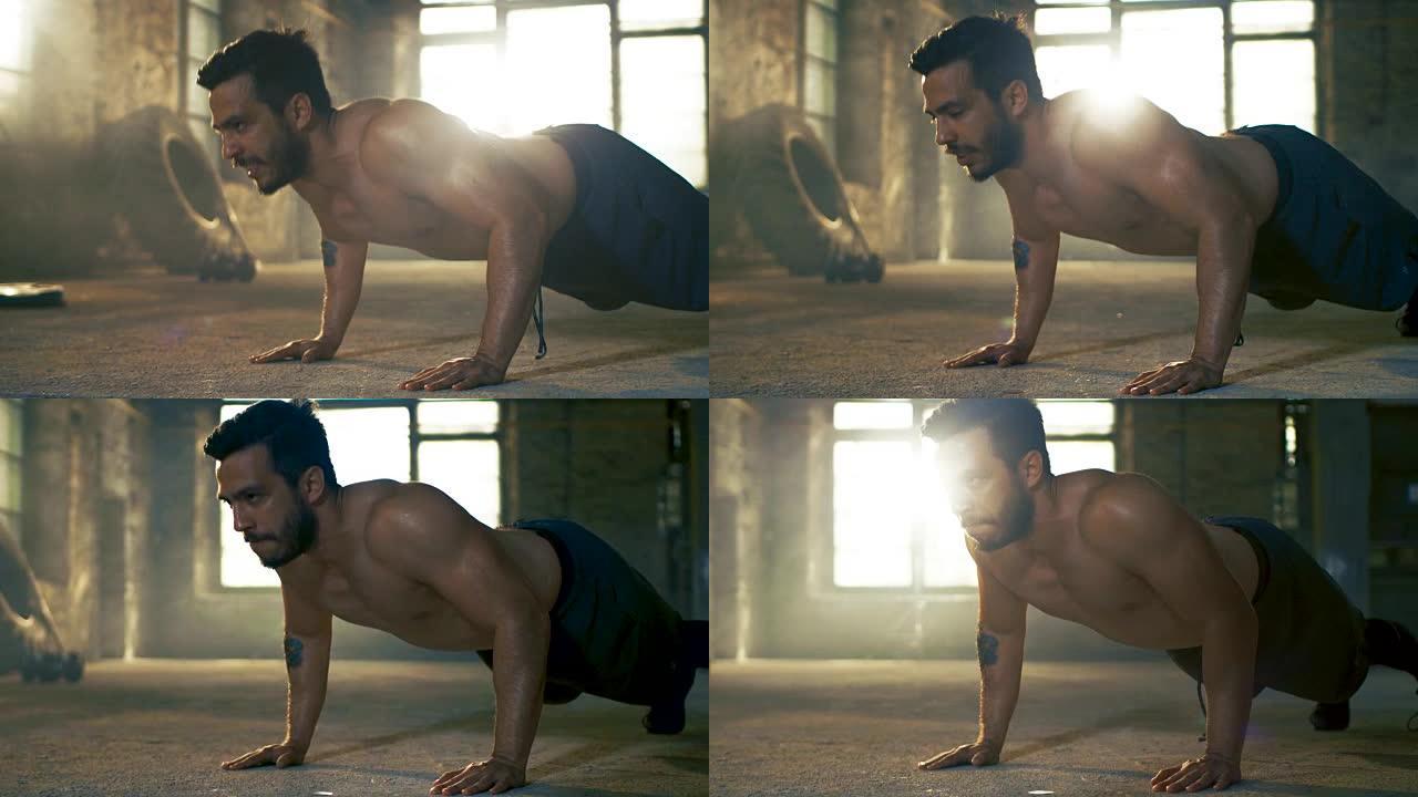 肌肉赤裸的男人在一个废弃的工厂改造成的健身房做俯卧撑。这是他的健身训练/高强度间歇训练的一部分。