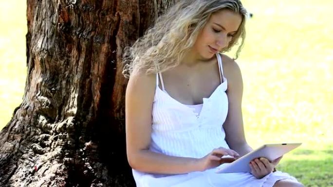 女人坐在公园里用电子书