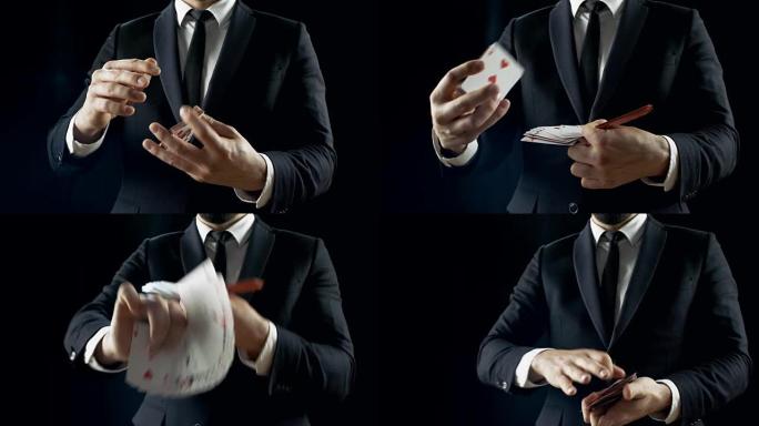 专业魔术师在一个黑色的西装表演卡戏法显示他的技能，使扇子出牌。背景是黑色的。