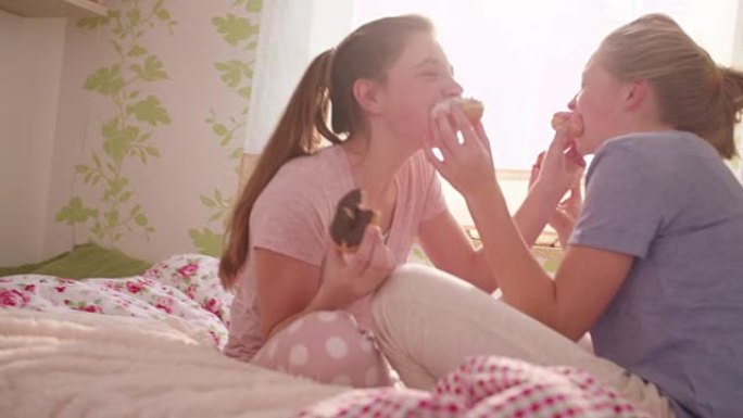 青春期女孩在五颜六色的卧室里互相喂食甜甜圈