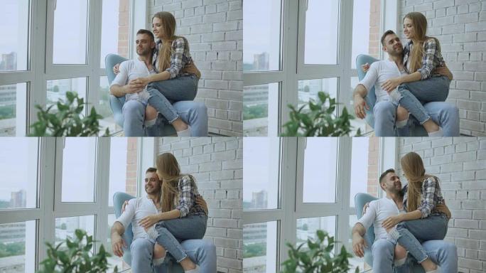 美丽的年轻夫妇坐在椅子上放松，从新阁楼公寓的阳台上欣赏风景