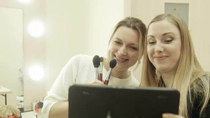 客户使用平板电脑与化妆师自拍