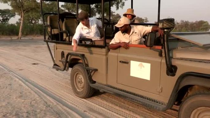 博茨瓦纳，游客和野生动物园向导在车辆后方观察动物轨迹