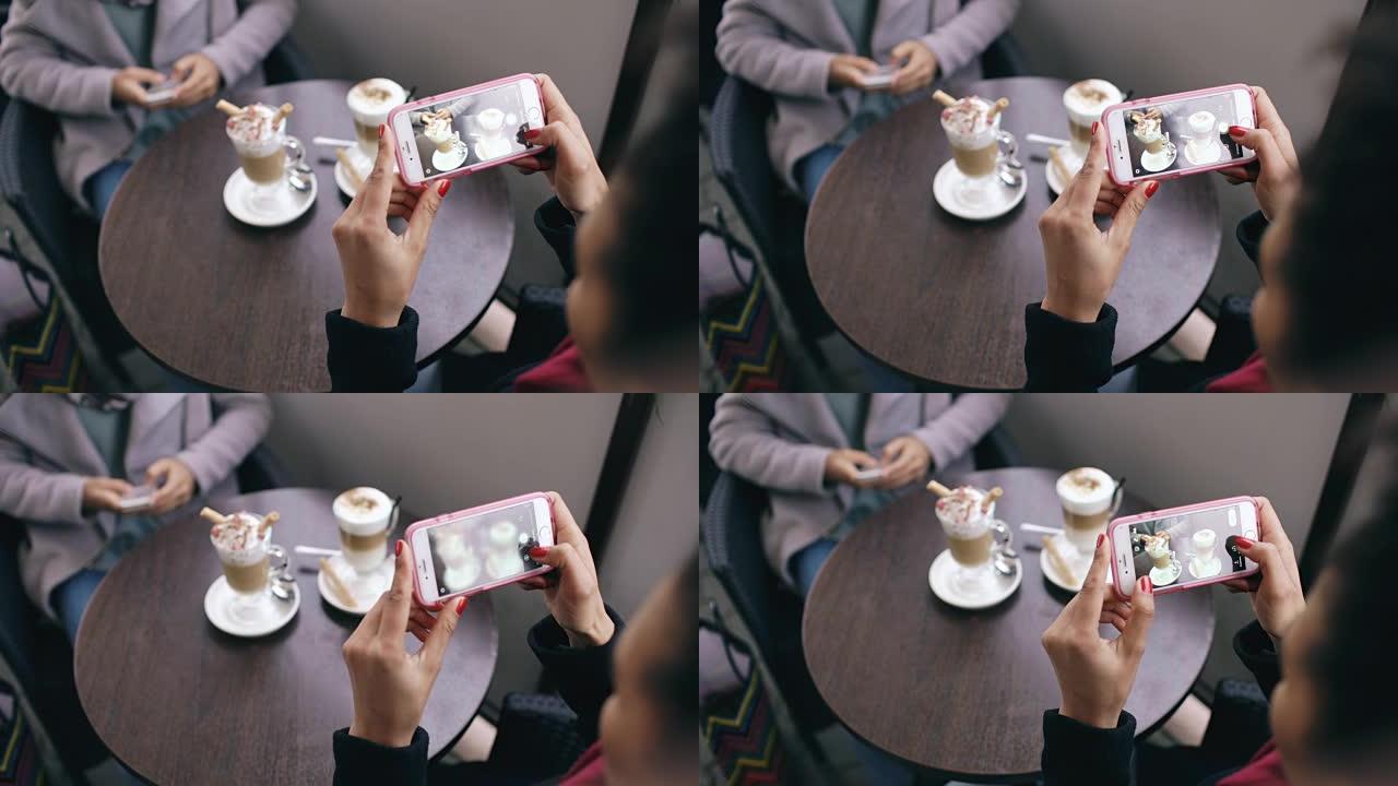 坐在户外街头咖啡馆时，女人用智能手机拍摄咖啡杯的特写镜头