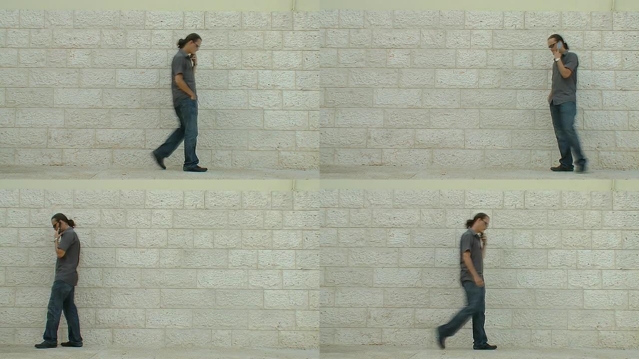 一名男子在白色砖墙附近拿着手机