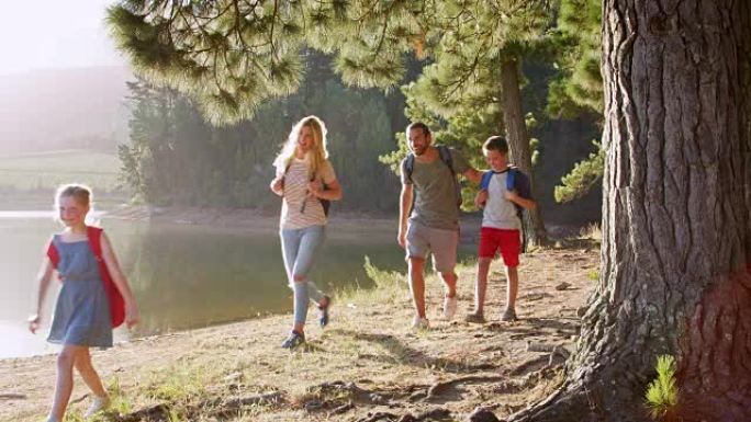 一家人徒步旅行，沿着湖旁的树林漫步