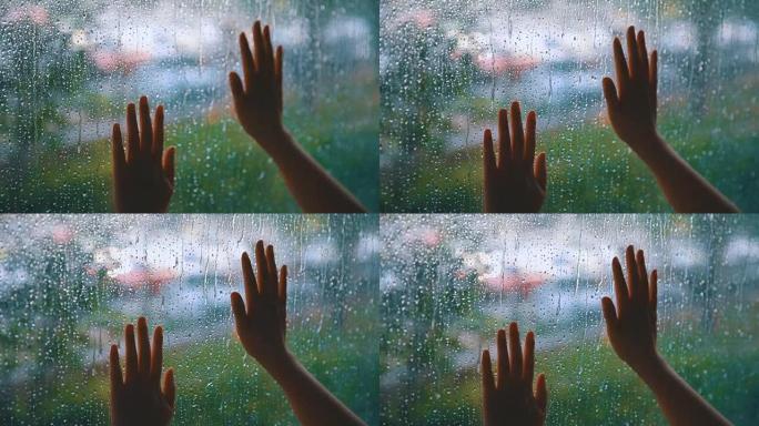 女人用手触摸雨滴的窗户