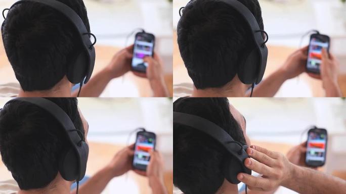 戴着耳机的帅哥在智能手机上选择音乐