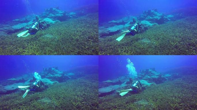 水肺潜水员在蓝色清澈的水中游泳的水下拍摄。