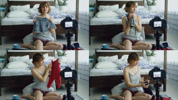 迷人开朗的女人坐在床边录制视频博客关于在家编织童装