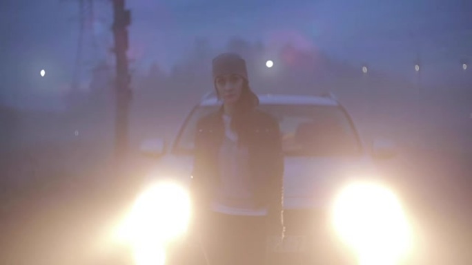 紧张的高加索女孩站在前灯附近。担心的女性在破碎的汽车附近迷路了，担心在黑暗的雾气高速公路上