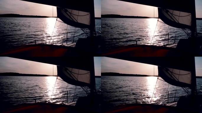 美丽的游艇在日落中穿越大海。帆板在傍晚全速穿越湖中的海浪