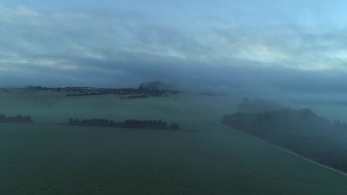 空中: 浓雾笼罩着草地和通往城镇的乡间小路