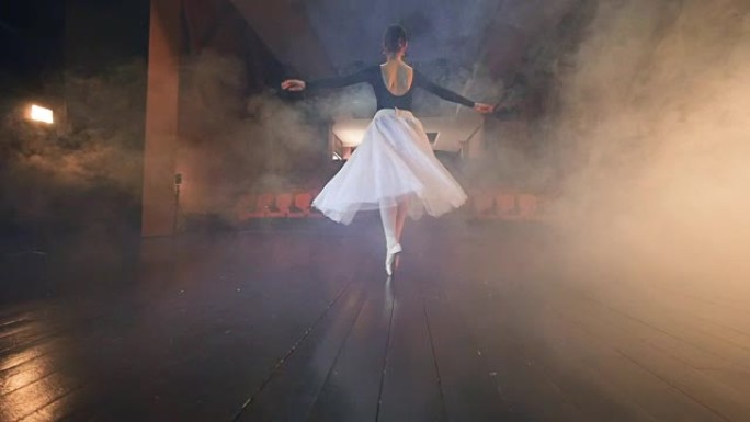 一个芭蕾舞演员在空座位的大厅里跳舞。