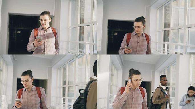 年轻英俊的高加索潮男学生正走在大学白光宽敞的走廊里，拿着电话打其他学生路过的电话