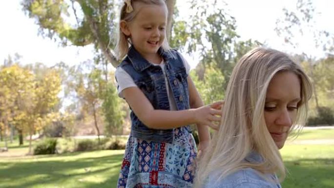 小女儿在公园编织母亲的头发，前视图