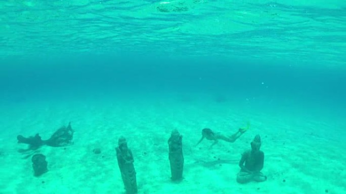 水下: 年轻女子在阳光明媚的暑假中，在热带岛屿泻湖海底沉没的佛像保护区周围游泳