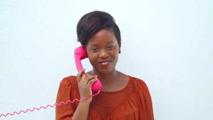 微笑快乐的年轻女子在粉红色的电话上聊天