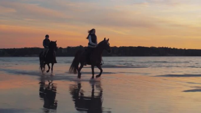 日落灯光下，两名马骑在海滩上。