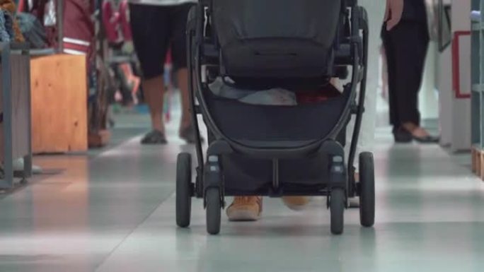 母亲和父亲在购物中心与婴儿车和婴儿一起散步