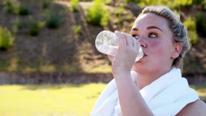 妇女在锻炼后喝水时擦汗
