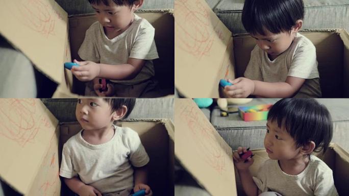 亚洲蹒跚学步的男孩练习用蜡笔画画