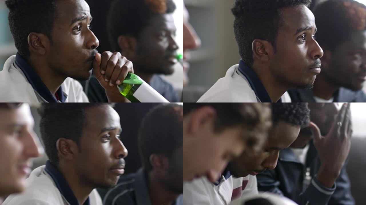 非洲男子喝啤酒和与朋友一起看足球