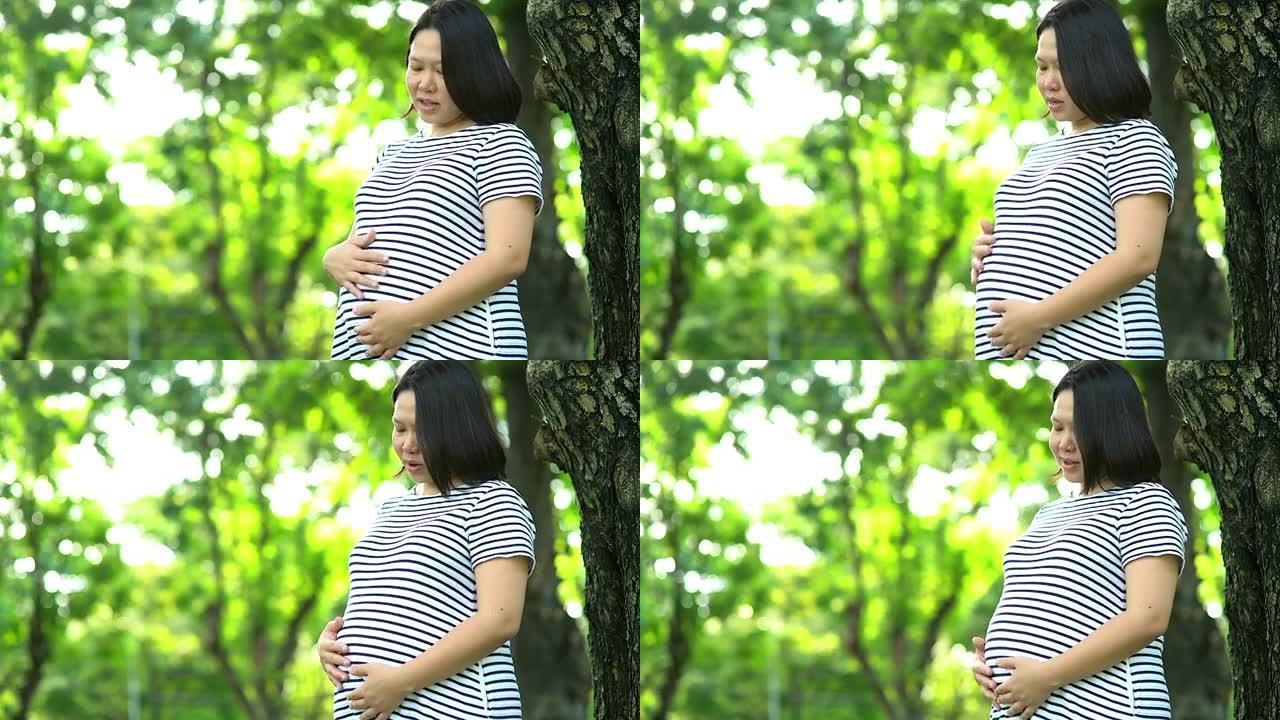 亚洲孕妇在公园摸肚子的肖像。
