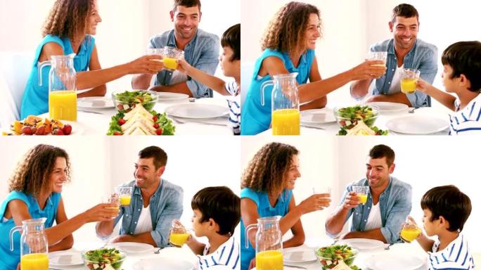 可爱的家庭午餐时用橙汁敬酒