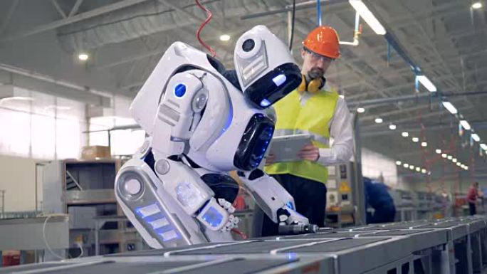 男性工厂员工正在打开机器人，然后它开始钻