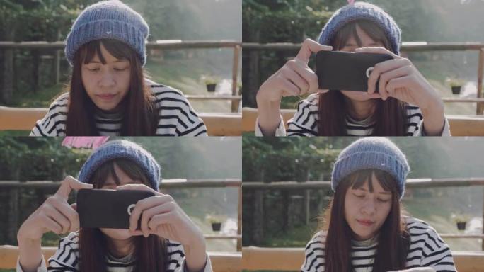 年轻的亚洲女性坐在户外使用智能手机。