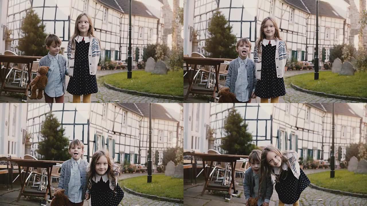 小女孩和男孩站在一起做鬼脸。欧洲兄弟姐妹看着相机傻笑。半木结构房屋4K