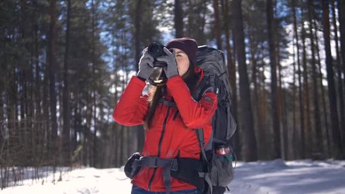 冬天森林里快乐的年轻女子用照相机拍照。