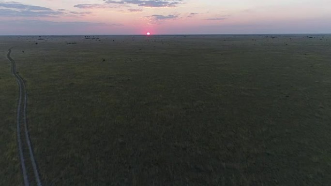 鸟瞰图的泥土路通过草原的博茨瓦纳走向夕阳