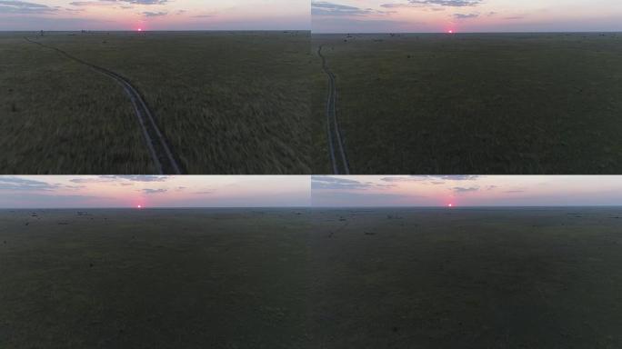 鸟瞰图的泥土路通过草原的博茨瓦纳走向夕阳