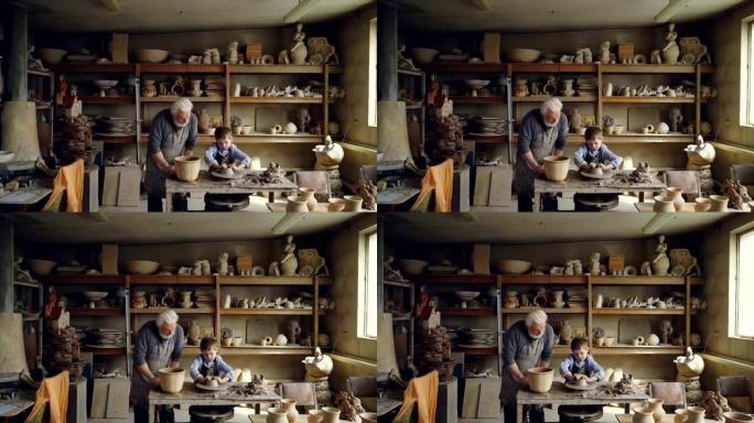 熟练的孩子在他的figuline家庭工作室与祖父一起工作时，正在波特的轮子上形成锅。专业设备和背景精