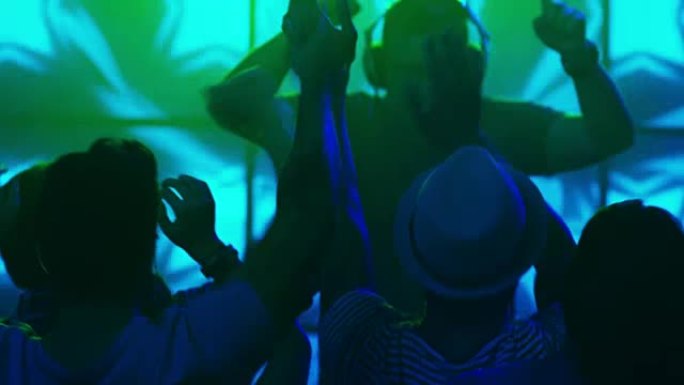 DJ在夜总会播放音乐，人们跳舞，玩得开心，举手。