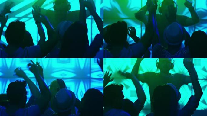 DJ在夜总会播放音乐，人们跳舞，玩得开心，举手。